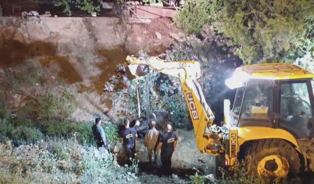 Düştüğü su kanalında çamura saplanan inek, kepçeyle kurtarıldı